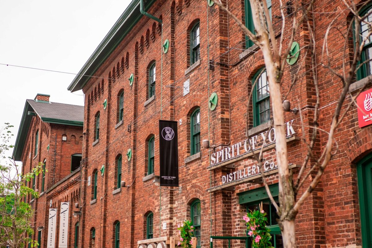 Edificios históricos de ladrillo rojo en Distillery District de Toronto con ventanas verdes y letrero vintage.