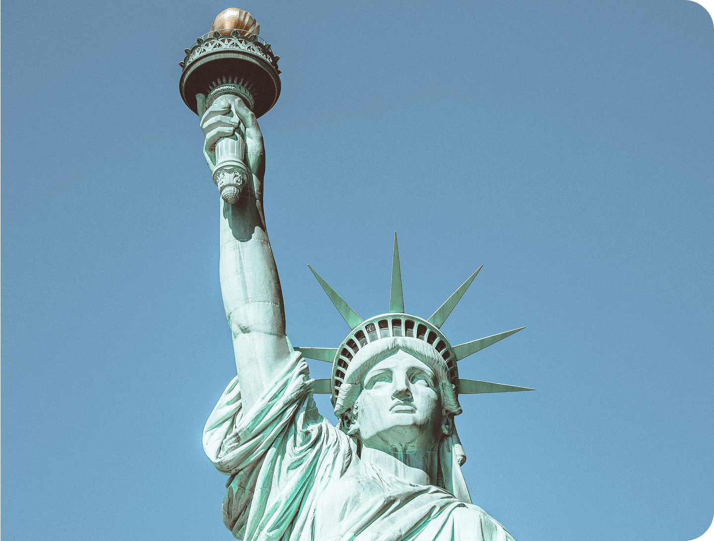 Estatua de la Libertad en Nueva York con antorcha elevada bajo cielo azul claro.
